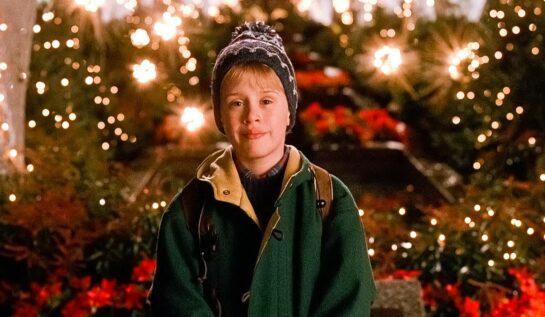 Macaulay Culkin în rolul principal din filmul Home Alone 2, îmbrăcat într-o geacă verde și fes pe cap.