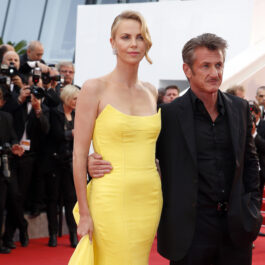 Charlize Theron pozează pe covoru roșu alături de Sean Penn îmbrăcată într-o rochie lungă, mulată și cu umerii goi