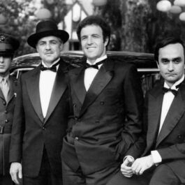 Fotografie alb-negru cu John Cazale și Al Pacino, James Caan și Marlon Brando îmbrăcați în costume negre în timpul filmărilor pentru ”Nașul”