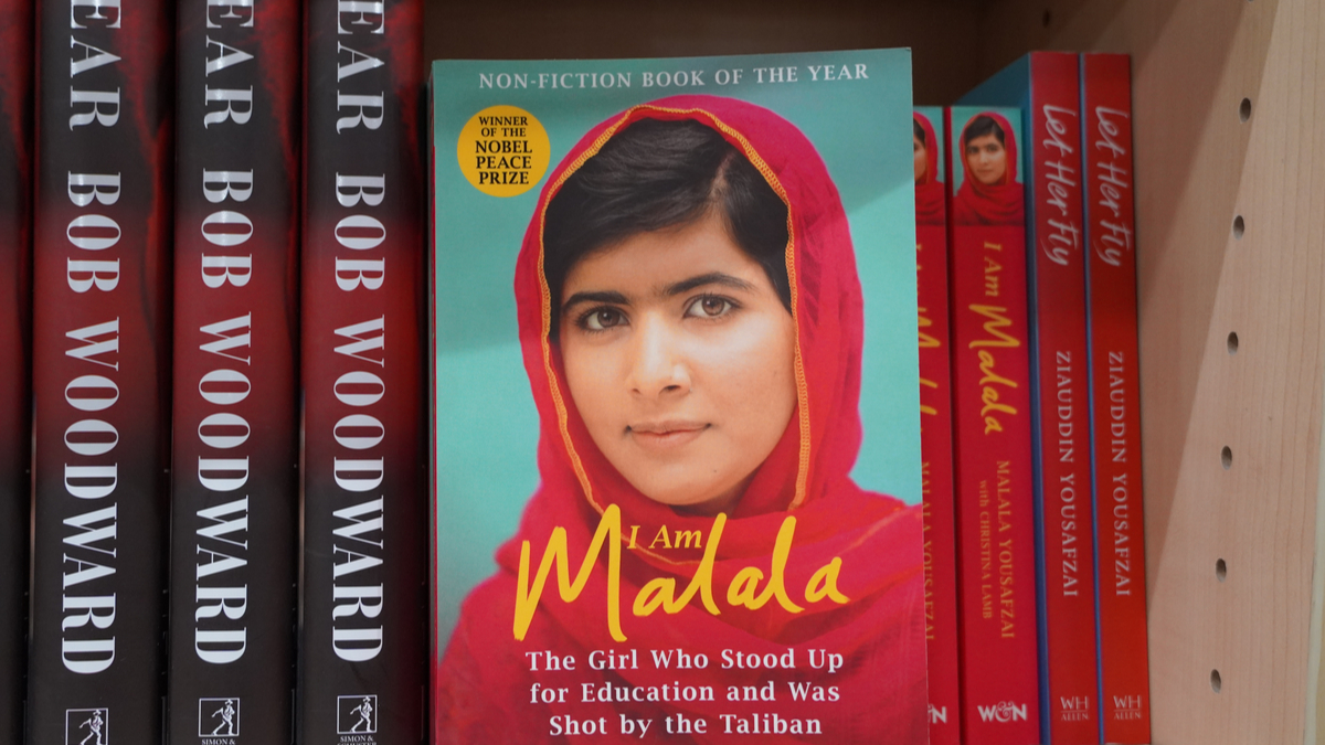 Cartea autobiografică a Malalei, cu portretul ei pe copertă, este așezată pe un raft