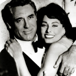 Fotografie alb-negru cu Sophia Loren îmbrățișânu-l pe Cary Grant pe o canapea