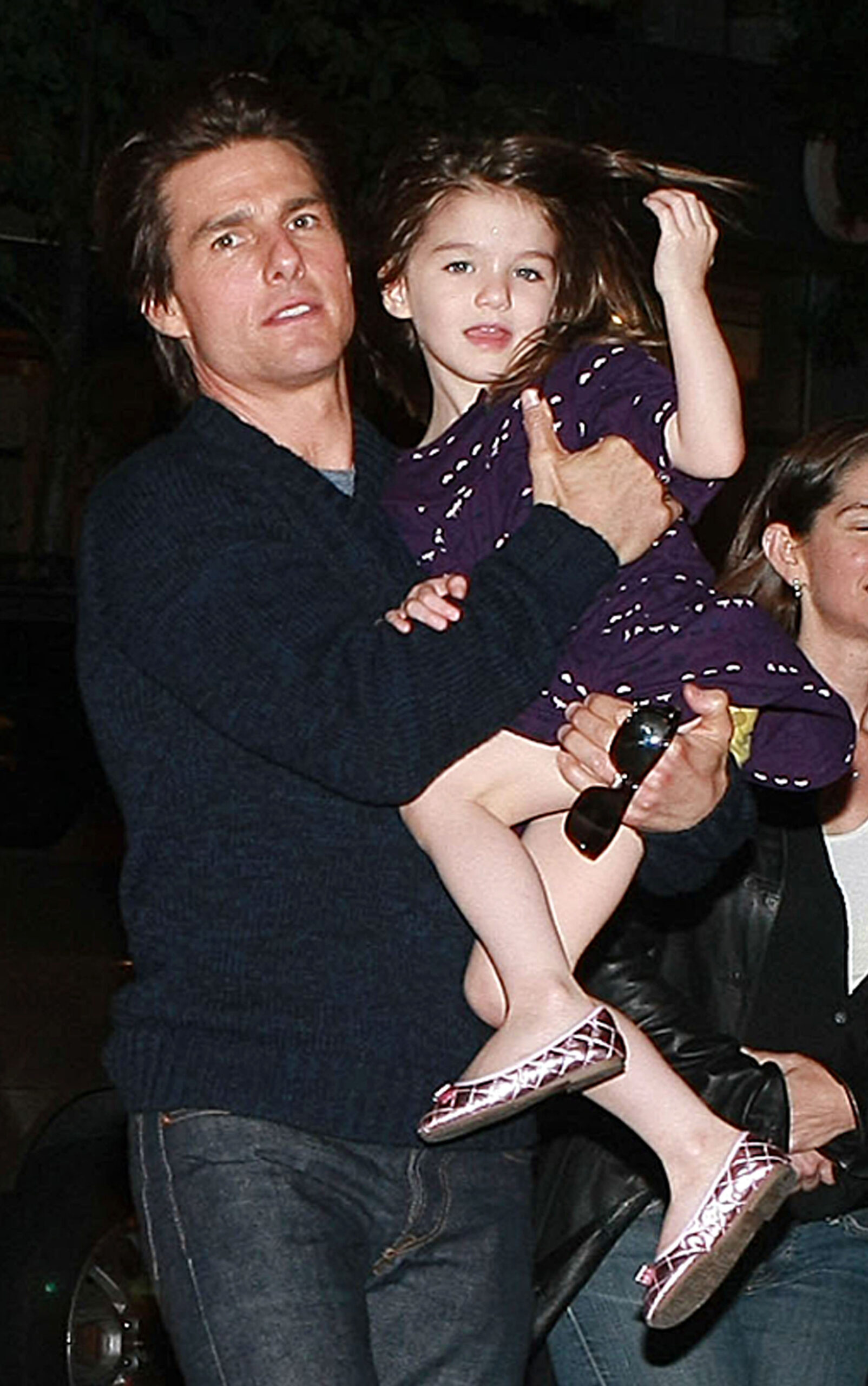 Suri Cruise în brațele tatălui său, Tom Cruise, în 2009, după filmările Wichita. Tom poartă o cămașă neagră, Suri e îmbrăcată într-o rochie mov