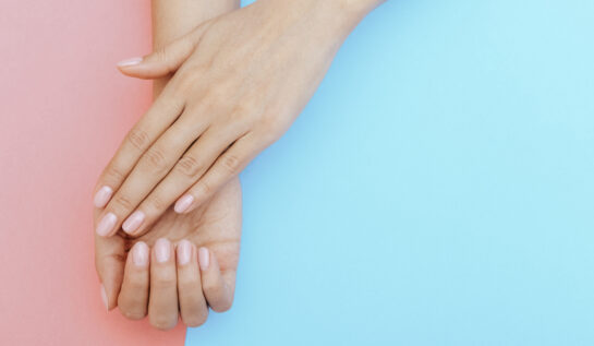 Două mâini cu manichiură transparentă pe un fundal albastru și roz