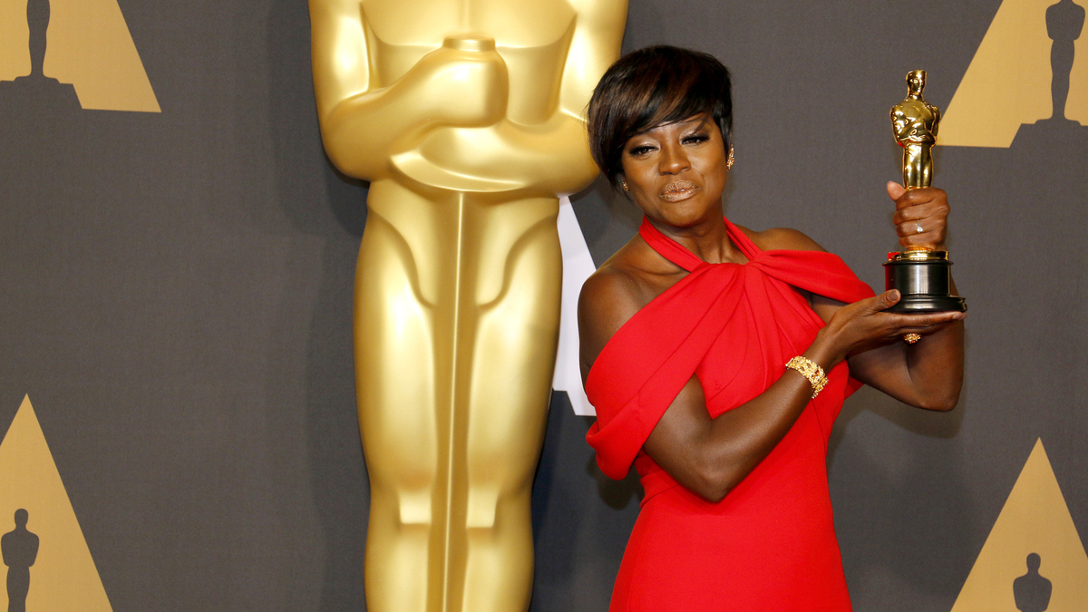 Viola Davis îmbrăcată într-o rochie roșie țină în mână o statuetă Oscar