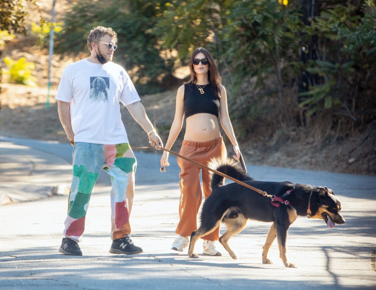 Emily Ratajkowski și soțul ei, Sebastian Bear-McClard, surprinși în timp ce își plimbă câinele într-un cartier din Los Angeles. Modelul poartă o bustieră neagră care îi lasă burtica de gravidă la vedere.