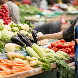 O femeie care alege legume la piață