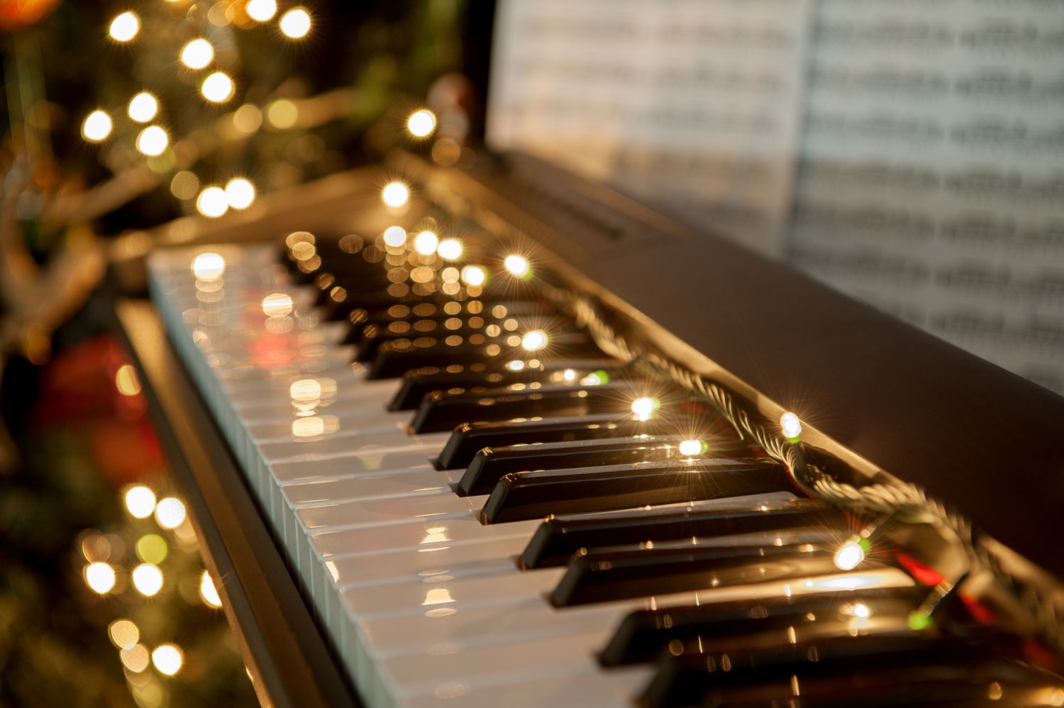 Un pian, pe care e așezată o instalație de brad și o partitură cu piese de Crăciun.