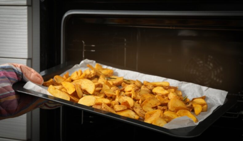 O tavă cu plină cu cartofi tăiați, pregătiți pentru cuptor pentru a obține cei mai crocanți cartofi la cuptor
