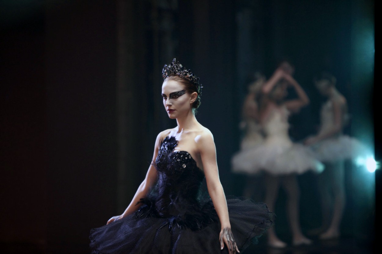 Natalie Portman poartă o rochie albastră de balerină și este ictată pe față cu vopsea albă și albastră