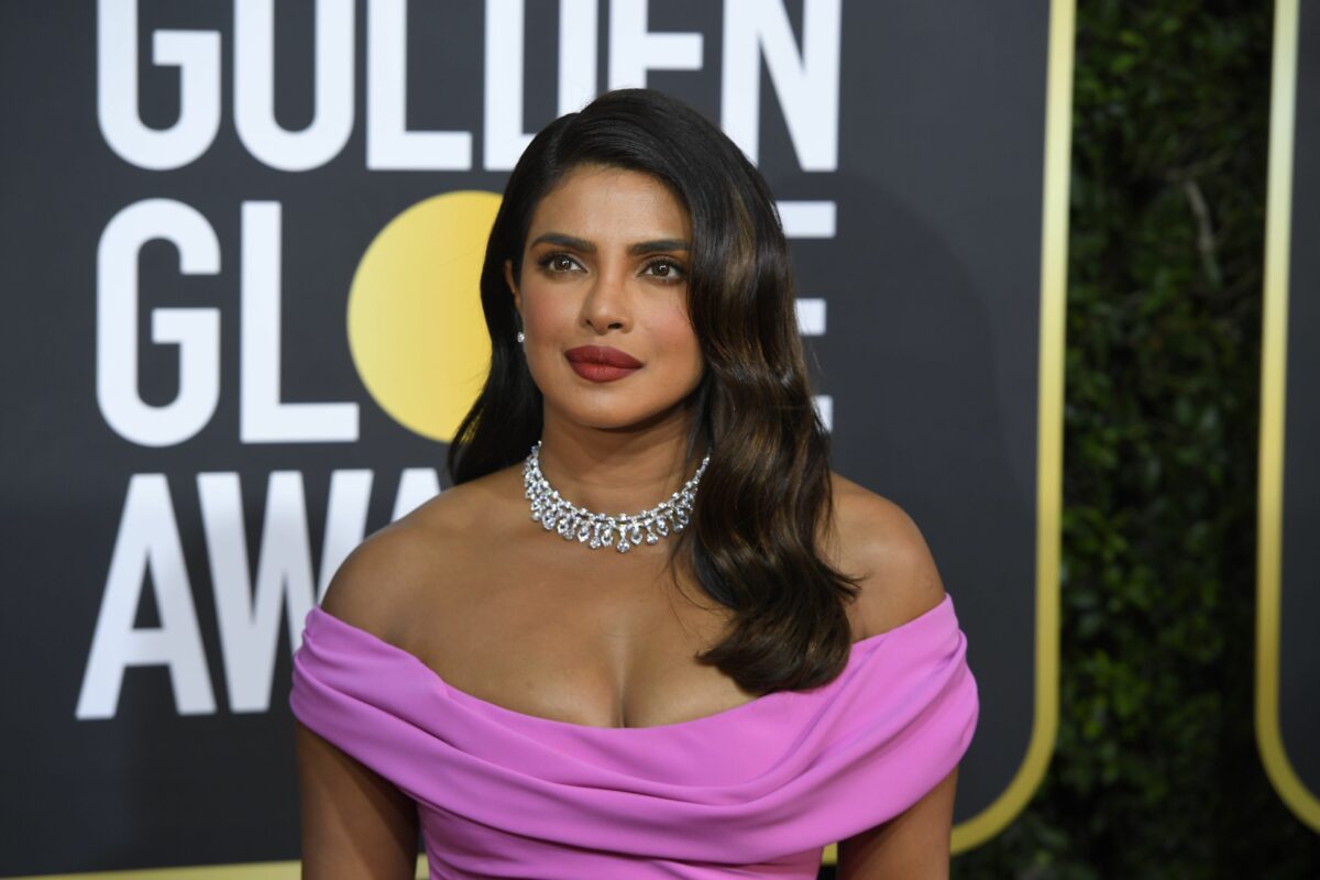 Priyanka Chopra îmbrăcată într- rochie mov cu umerii dezgoliți și un colier pe covorul rosu de la Golden Globe Awards