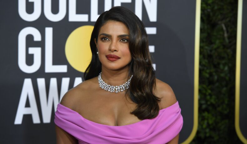 Priyanka Chopra îmbrăcată într- rochie mov cu umerii dezgoliți și un colier pe covorul rosu de la Golden Globe Awards