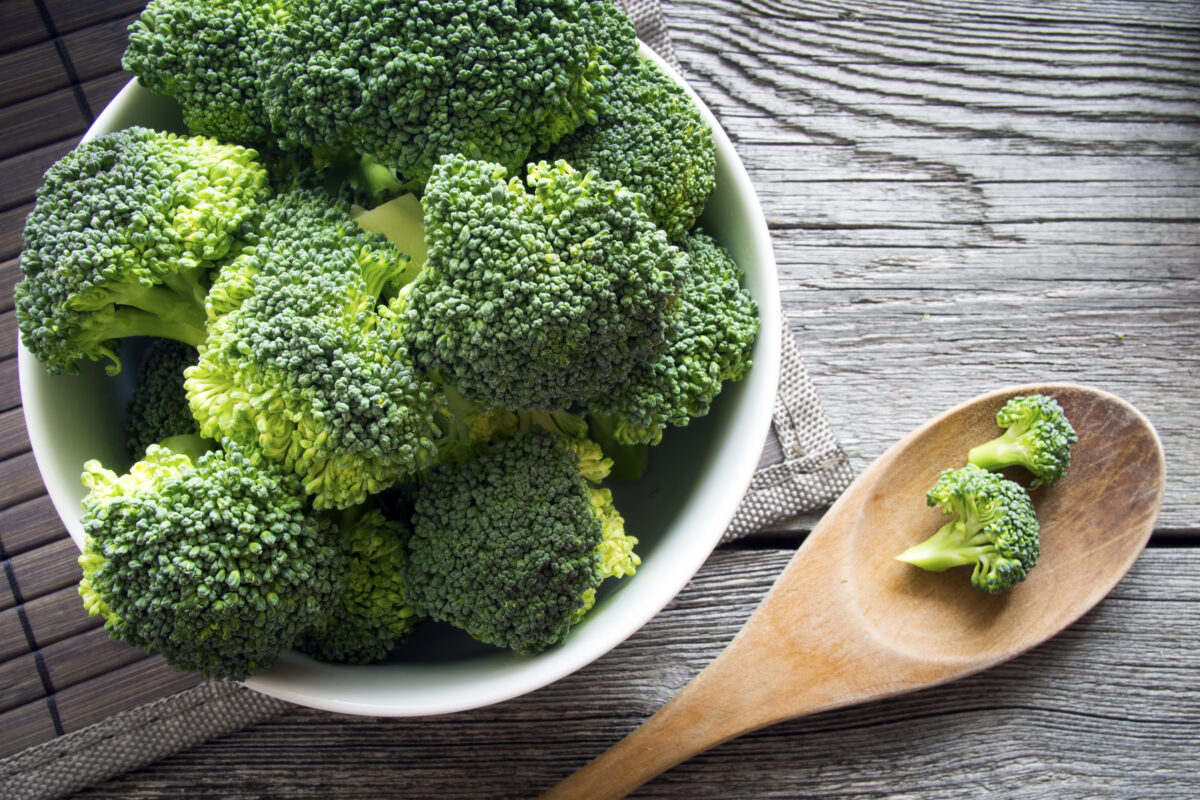 Imagine cu un bol de broccoli verde și o lingură de lemn alături