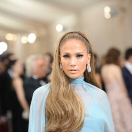 Jennifer Lopez poartă o rochie albastru deschis și are părul prins într-o coadă elegantă