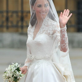 Kate Middleton îmbrăcată în rochie de mireasă și cu voalul pe faț salută mulțimea