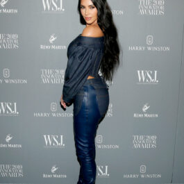 Kim Kardashian îmbrăcată cu o cămașă albasră din denim, blugi și cizme peste genunchi albastre din piele