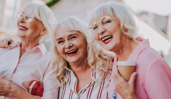 Trei femei în vârstă se îmbrățișează și râd