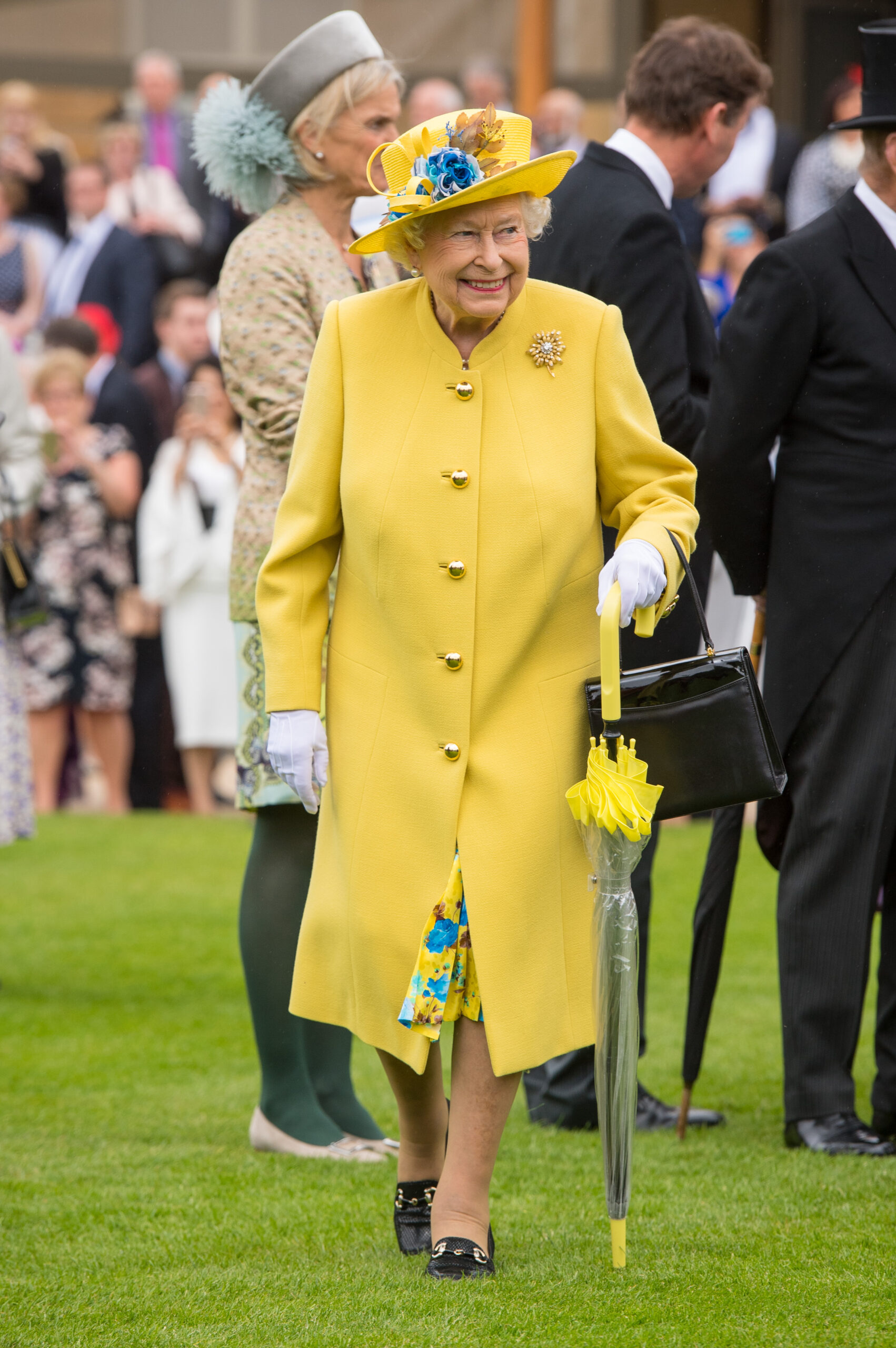 Regina Elisabeta la un eveniment public, îmbrăcată într-o ținută elegantă, galbenă