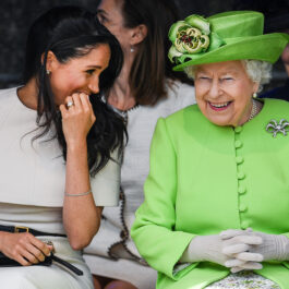 Regina Elisabeta alături de Meghan Markle la un eveniment în public, în care Regina poartă mănuși