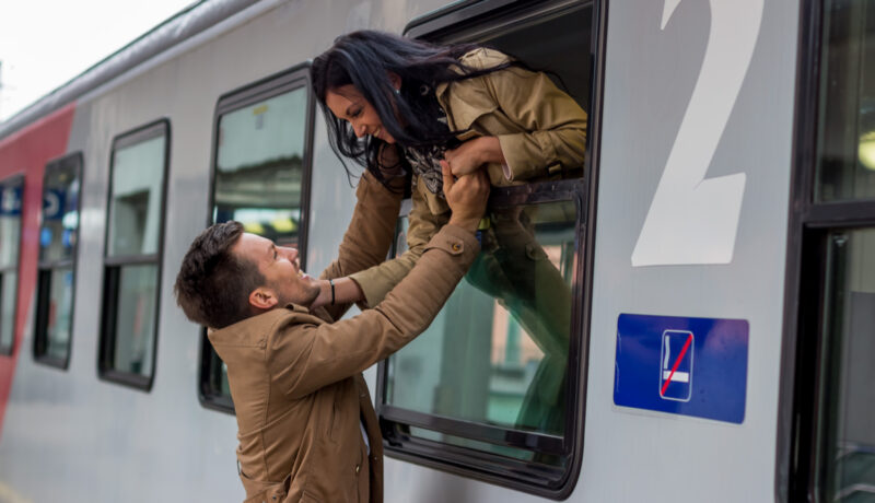 O fată e apleacă pe fereastra unui tren pentru a-și îmbrățișa iubitul