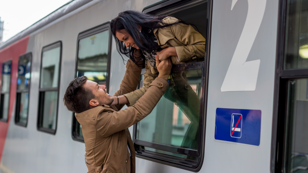 O fată e apleacă pe fereastra unui tren pentru a-și îmbrățișa iubitul