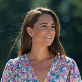 Kate Middleton îmrăcată cu o rochie mov cu flori, machiaj natural și părul pe spate
