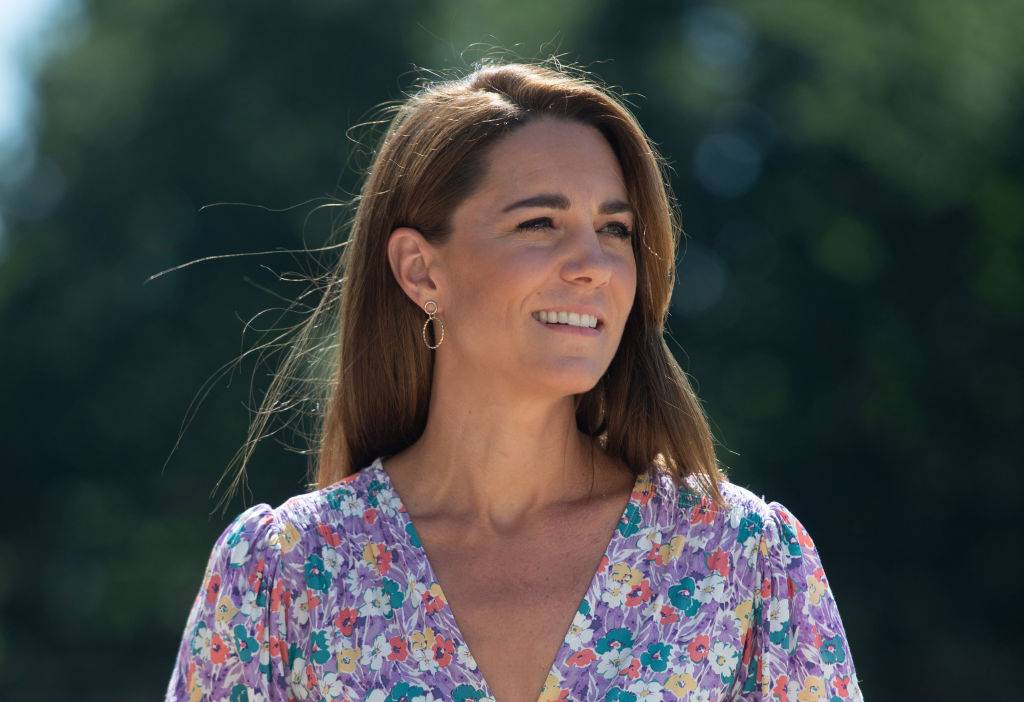 Kate Middleton îmrăcată cu o rochie mov cu flori, machiaj natural și părul pe spate