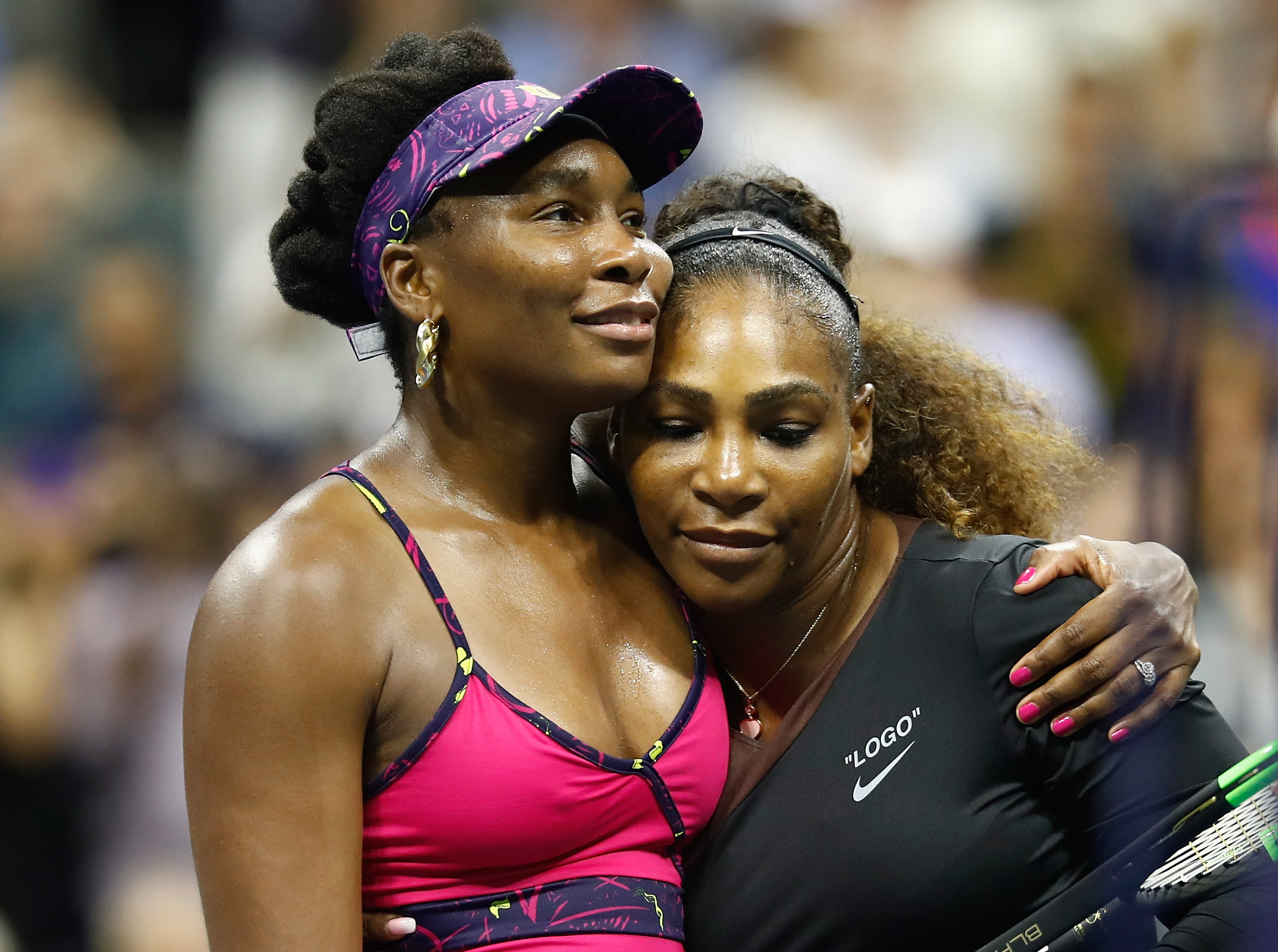 Serena Williams și Venus Williams pe terenul de tenis, îmbrățișate
