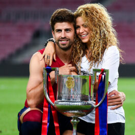 Shakira îl îmbrățișează pe Gerard Pique pe terenul de fotbal. În fața lor este o cupă de fotbal