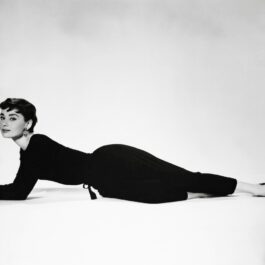 Poză alb-negru cu Audrey Hepburn încălțată cu balerini negri șă îmbrăcată într-o ținură neagră