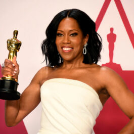 Regina King pe covorul roșu la Oscar cu o statuetă în mână, îmbrăcată cu o rochie albă fără bretele