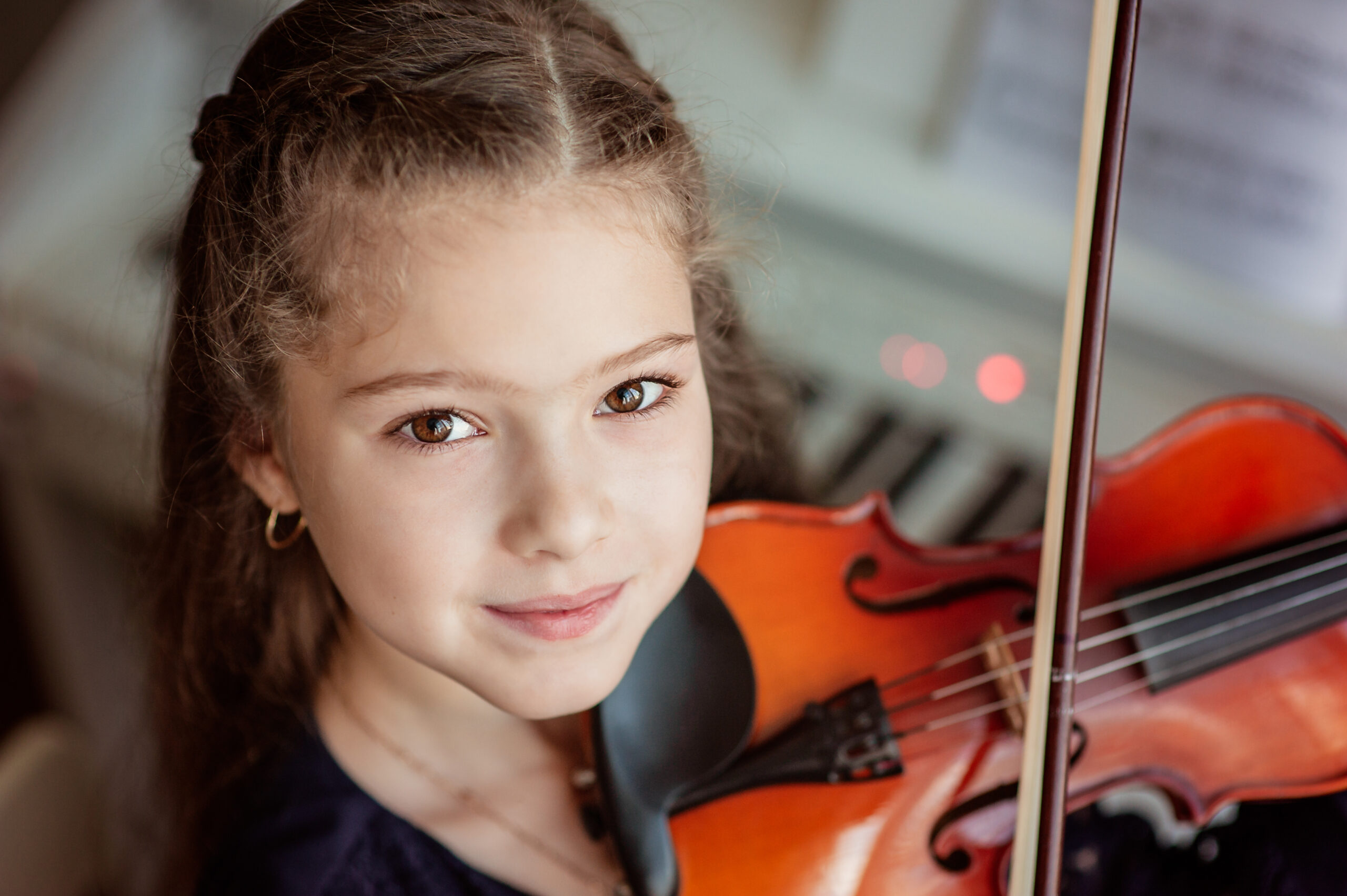O fată cu părul lung șaten cântă la vioară