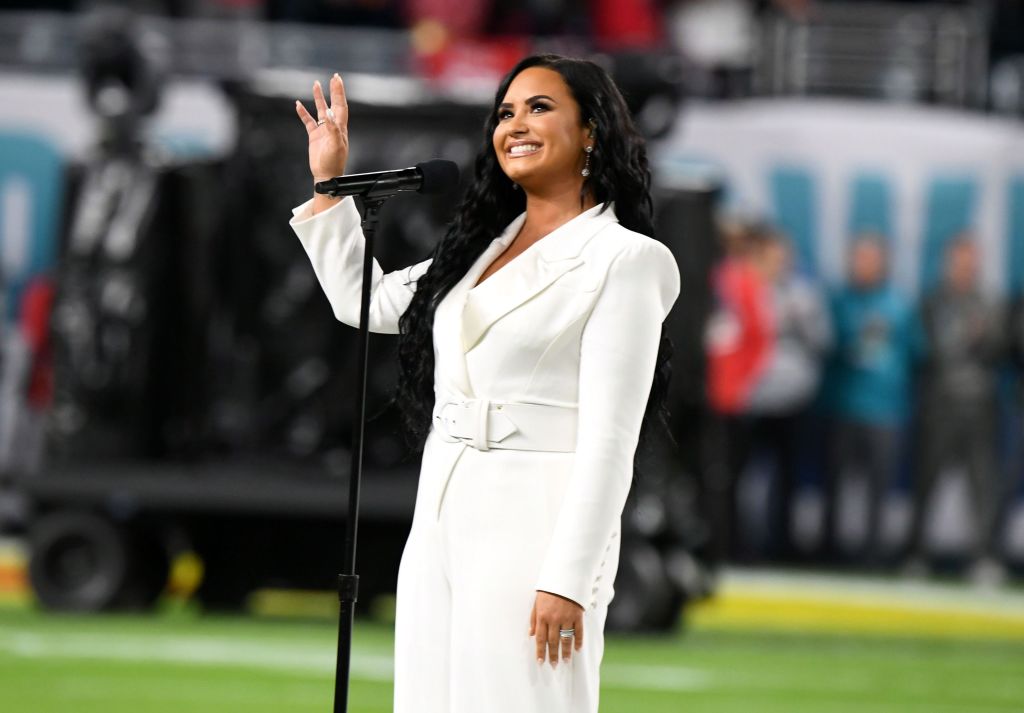 Demi Lovato în timp ce își salută publicul la Super Bowl 2021, îmbrăcată într-o ținută albă
