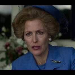 Gillian Anderson îmbrăcată cu un sacou albastru și o pălărie albastră în rolul lui Margaret Thatcher