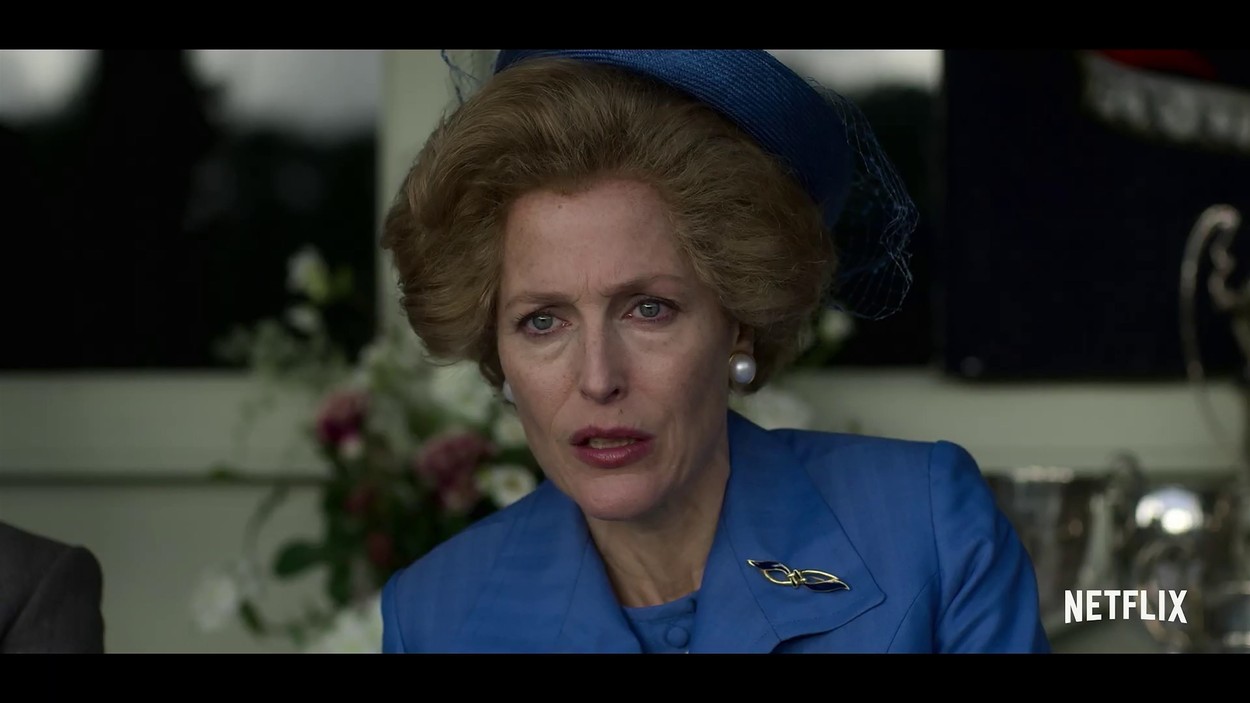 Gillian Anderson îmbrăcată cu un sacou albastru și o pălărie albastră în rolul lui Margaret Thatcher