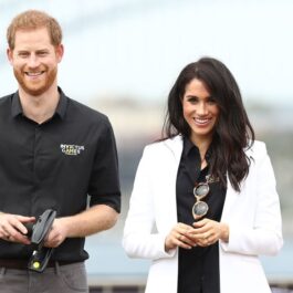 Meghan Markle și Prințul Harry zâmbesc în timp ce participă la un eveniment