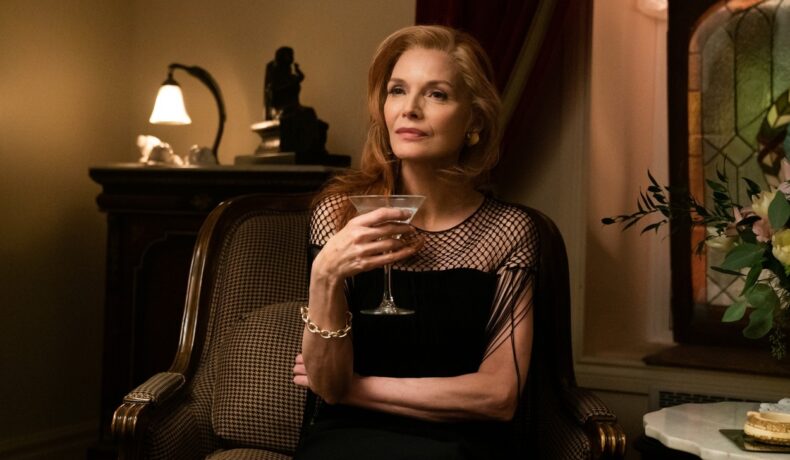 Michelle Pfeiffer îmbrăcată într-o rochie neagră ține un pahat de martini în mână