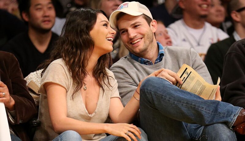Mila Kunis și Ashton Kutcher râd la un meci de baschet