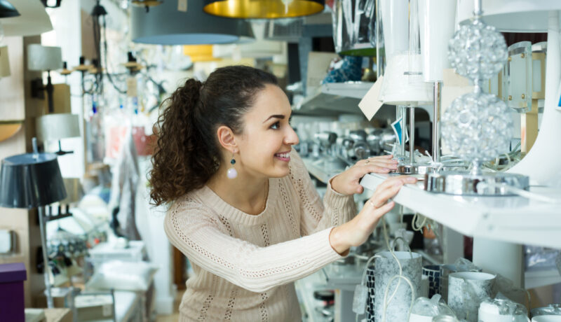 O femeie cu părul creț caută o lustră la raionul de lustre al unui magazin