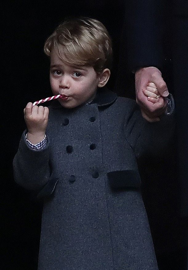 Prințul George într-un palton gri mănâncă o acadea