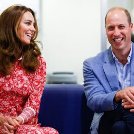 Prințul William și Kate Middleton sunt așezați pe o canapea și afișează zâmbete largi