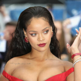 Rihanna într-o rochie roșie pe umeri prezentă pe covorul roșu