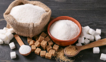 Zahărul granulat și zahărul brun depozitate în recipiente pe masă