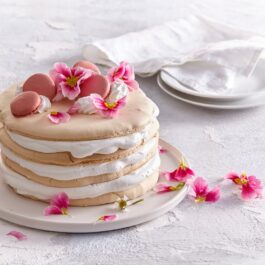 Tort pavlova decorat cu macarons și flori comestibile