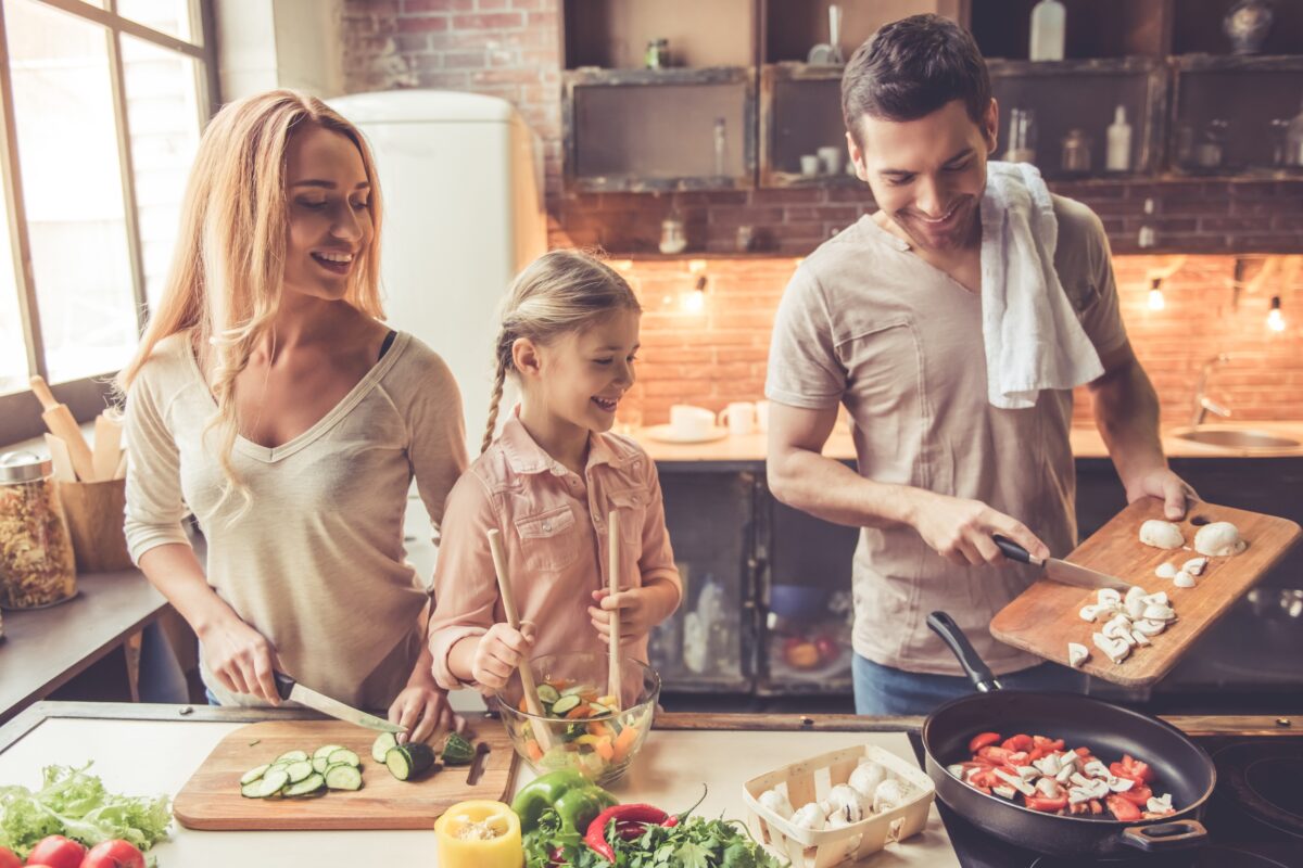 Un bărbat, o femeie și o fetiță gătesc împreună