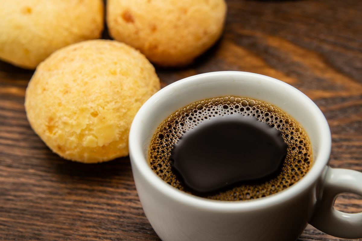 O ceașcă de cafea, alături de niște biscuiți, așezați pe o masă