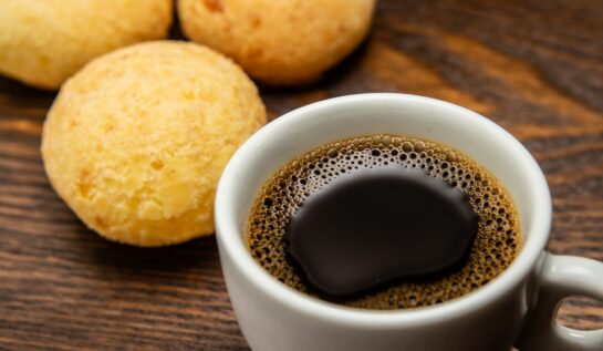 O ceașcă de cafea, alături de niște biscuiți, așezați pe o masă