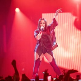 Demi Lovato pe scenă îmbrăcată cu o ereche de colanți negri decupați