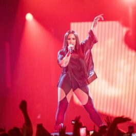 Demi Lovato pe scenă îmbrăcată cu o ereche de colanți negri decupați