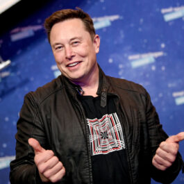 Elon Musk face semnul like cu ambele mâini în timp ce este fotografiat