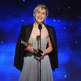 Emilia Clarke ține un trofeu în mână în timp ce susține un discurs pe scenă